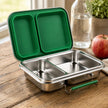Close-up of stainless steel medium lunchbox with two compartments, showcasing leak-resistant design on rustic wooden table with natural morning light.