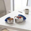 Two-pack snack pots with silicone lids, small with almonds and large with berry yogurt, set on a white background for office snack scene.