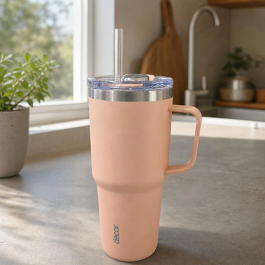 Insulated XL travel tumbler with lid and straw on modern kitchen countertop, showcasing matte stainless steel finish and reflection.